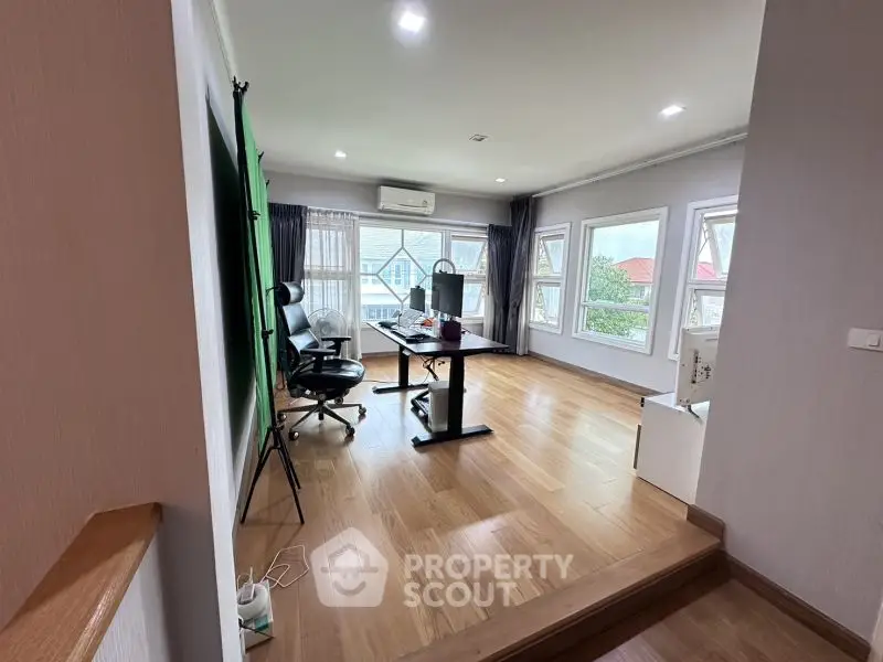 Spacious study room with modern desk and natural light from large windows.