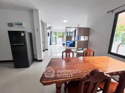 Spacious open-plan dining area with wooden table and chairs, adjacent to modern kitchen and living room.