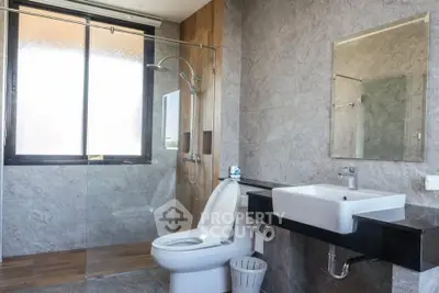 Modern bathroom with glass shower, sleek sink, and large window for natural light.