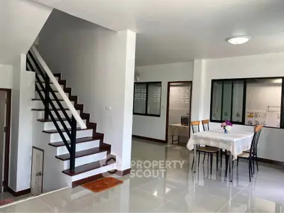 Modern dining area with staircase and sleek tiled flooring in a bright home interior.