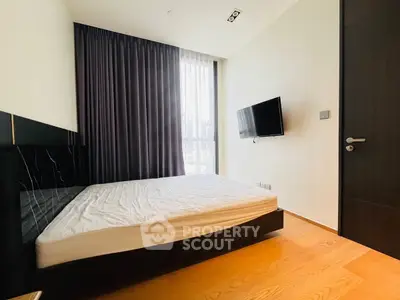 Modern bedroom with sleek design, featuring a wall-mounted TV and large window with city view.