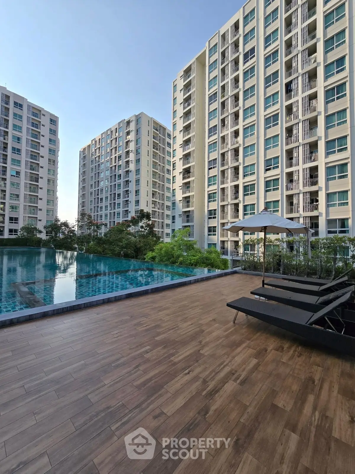 Luxurious residential complex with poolside relaxation area and modern high-rise buildings.