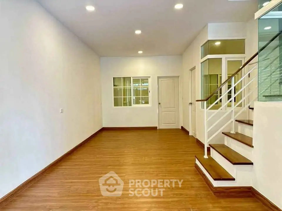 Spacious interior with wooden flooring and modern staircase, ideal for open living.