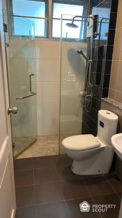 Modern bathroom with glass shower enclosure, sleek fixtures, and tiled flooring, offering a clean and contemporary living space.