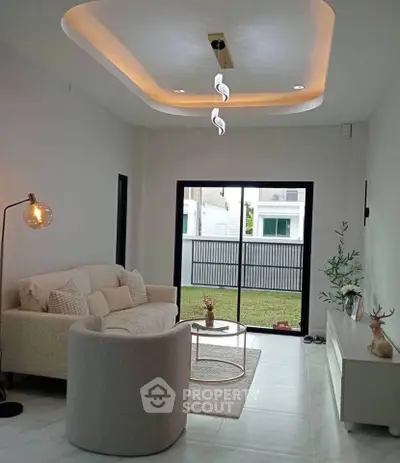 Stylish modern living room with elegant lighting and cozy seating area, overlooking a serene garden view.
