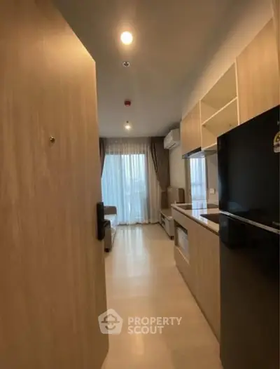 Modern apartment entrance leading to a cozy living space with kitchen and natural light.