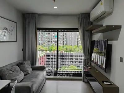 Modern living room with city view, featuring a cozy sofa and wall-mounted TV.