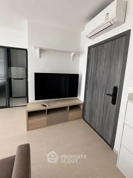 Modern living room with sleek TV setup and air conditioning in a stylish apartment.