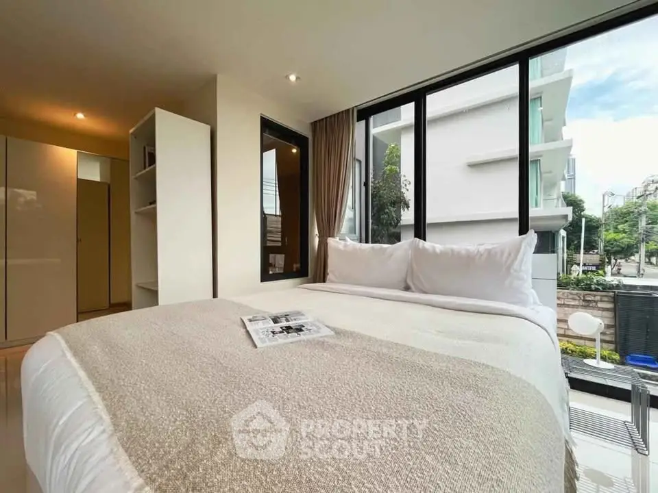 Modern bedroom with large windows and cozy bedding in a stylish apartment