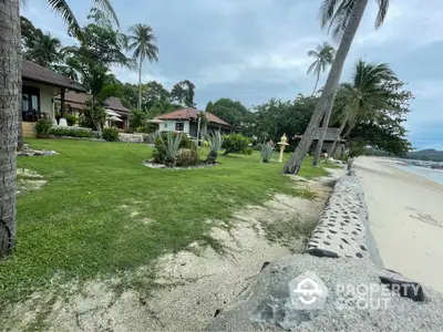 Beachfront property with lush garden and palm trees offering serene coastal living.