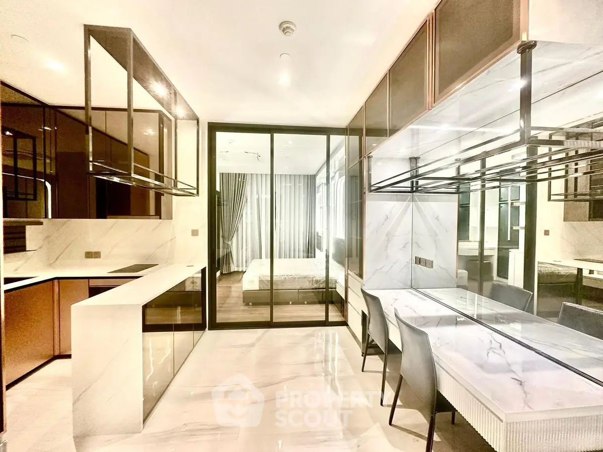 Luxurious modern kitchen with sleek design and open layout, featuring elegant dining area and view into bedroom.