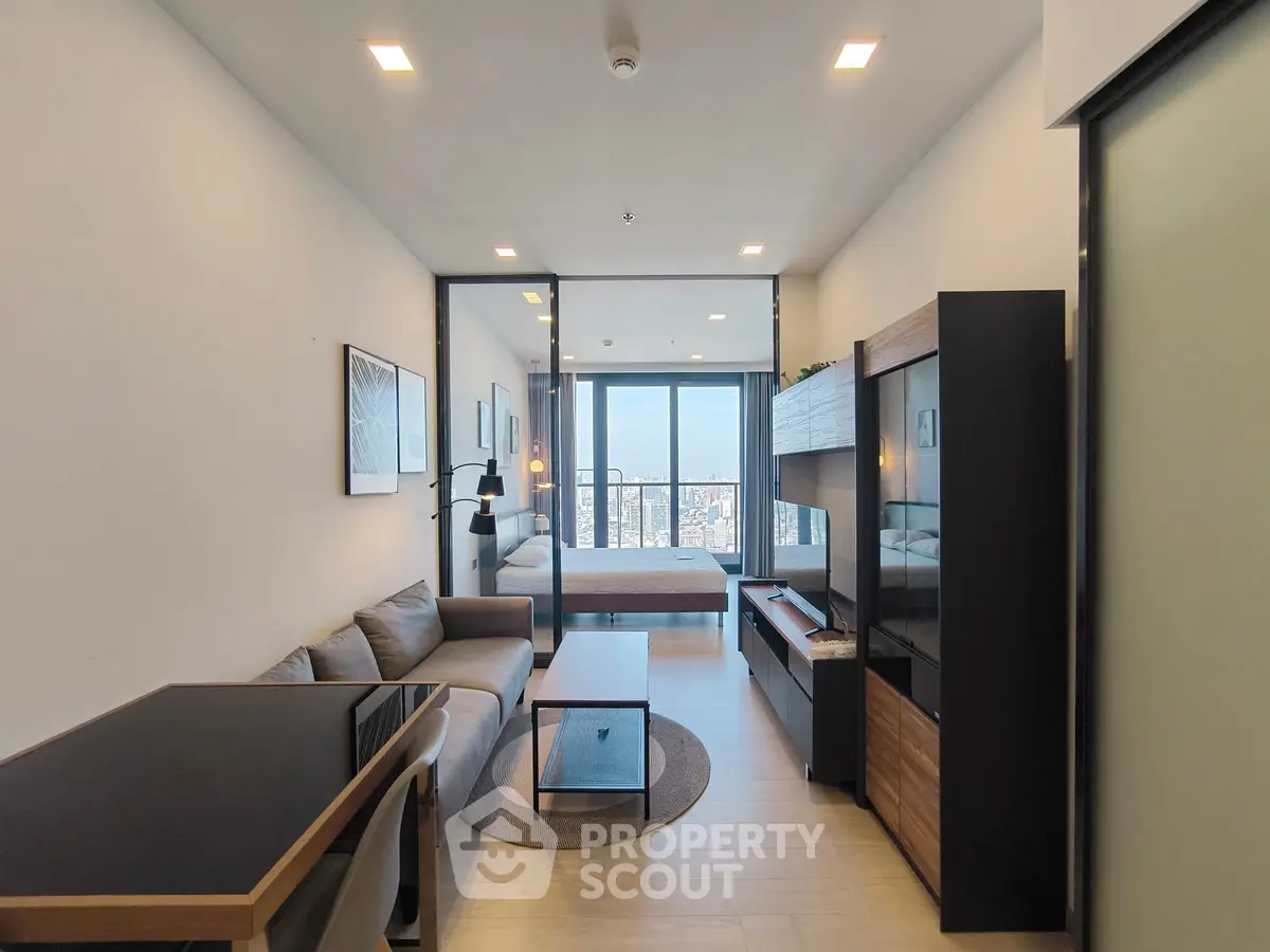Modern open-plan living room with stylish furniture and city view from the balcony.