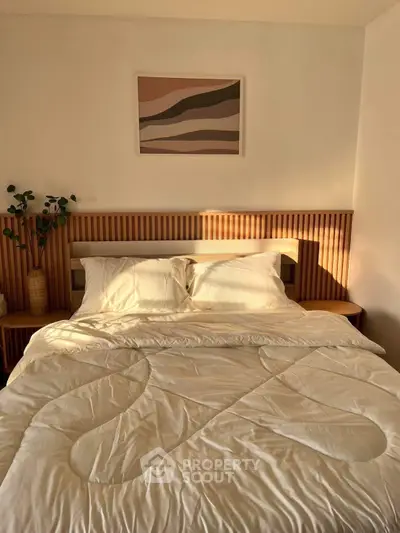 Cozy bedroom with modern decor and warm sunlight streaming through, highlighting the stylish bed and artwork.
