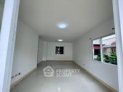 Spacious empty room with large windows and glossy tiled floor, ideal for customization.