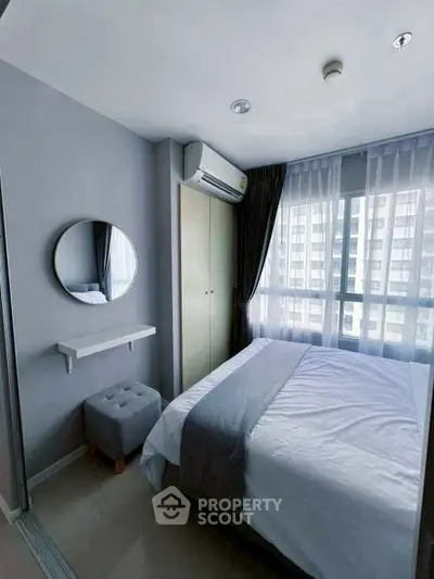 Modern bedroom with natural light, stylish decor, and air conditioning in a high-rise apartment.