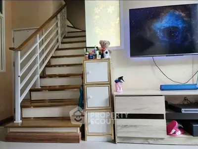 Charming living room with modern staircase and wall-mounted TV, perfect for cozy family gatherings.