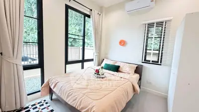 Bright and cozy bedroom with large windows and modern decor, perfect for relaxation.