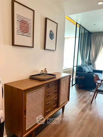 Stylish living room with modern decor and wooden flooring, featuring elegant furniture and artistic wall frames.