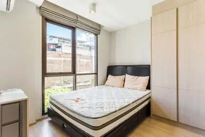 Bright bedroom with large window and modern furnishings in a stylish apartment.
