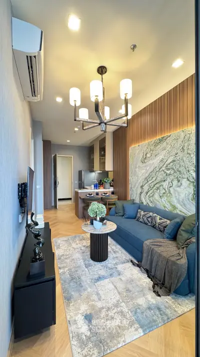 Modern living room with stylish decor and open kitchen layout, featuring elegant lighting and cozy seating.
