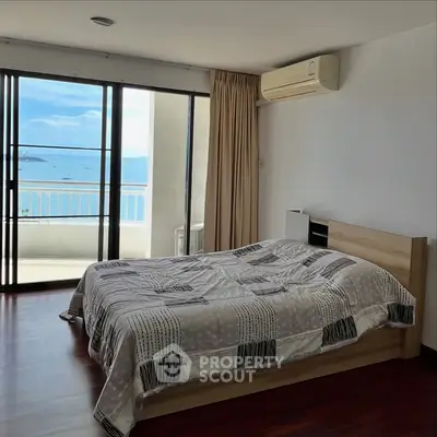 Spacious bedroom with stunning ocean view and balcony access in modern apartment.