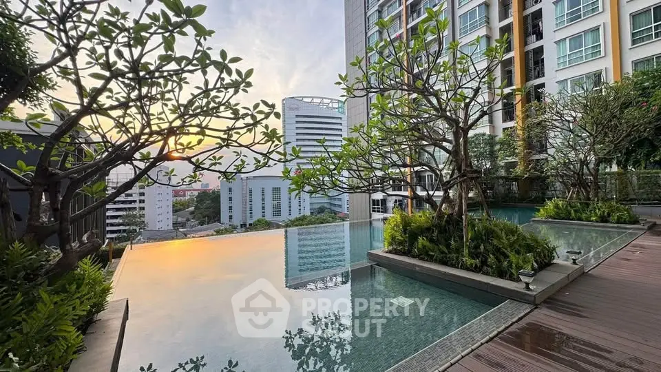 Luxurious rooftop pool with stunning city view and lush greenery at sunset.