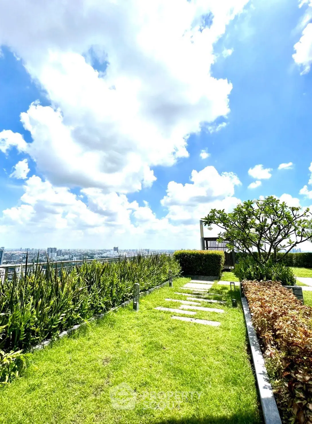 Stunning rooftop garden with panoramic city views and lush greenery under a bright blue sky.