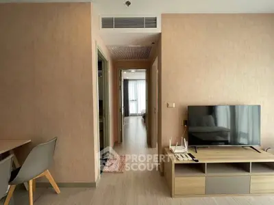 Modern living room with sleek furniture and neutral tones, featuring a flat-screen TV and stylish decor.