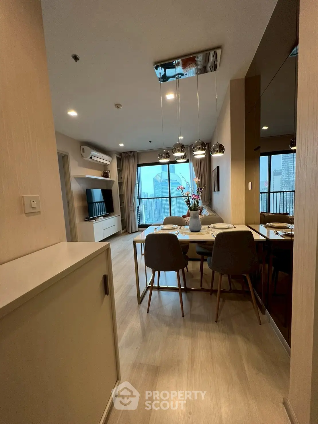 Modern open-plan living and dining area with stylish decor and city view balcony.