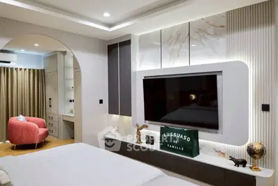 Luxurious modern bedroom with stylish decor and large TV, featuring elegant lighting and a cozy seating area.