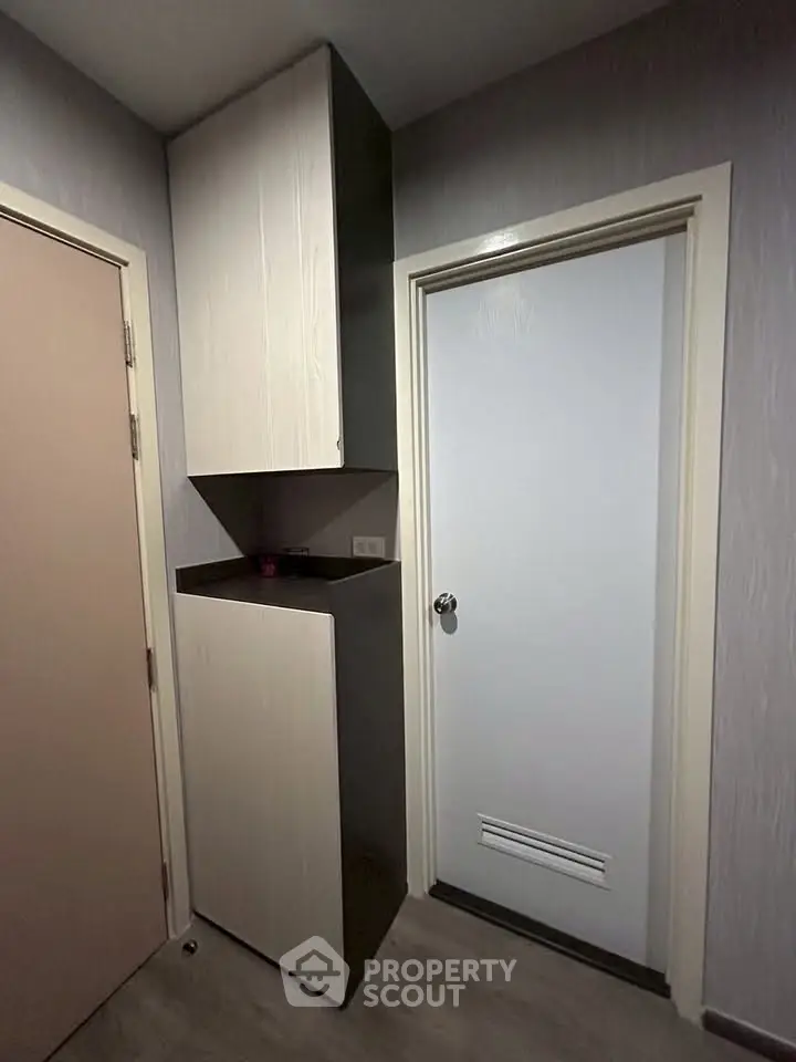 Compact storage area with modern cabinetry and two doors in a residential unit.