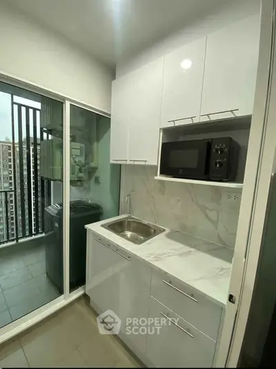 Modern kitchen with sleek white cabinets and balcony view in urban apartment