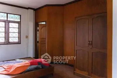 Spacious bedroom with wooden wardrobe and large window, perfect for cozy living.