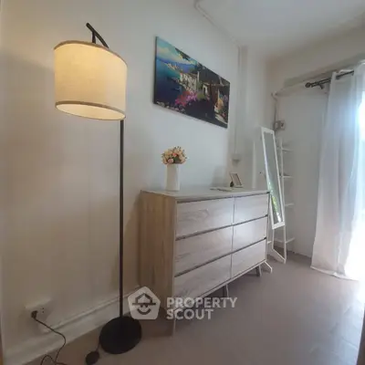 Charming bedroom corner with modern dresser and floor lamp, perfect for cozy living.