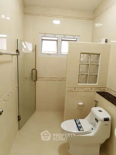 Modern bathroom with glass shower and sleek toilet design.