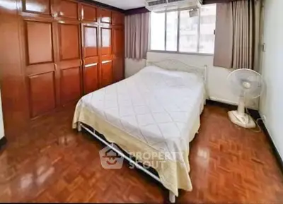 Spacious bedroom with wooden flooring and large wardrobe in a cozy apartment.