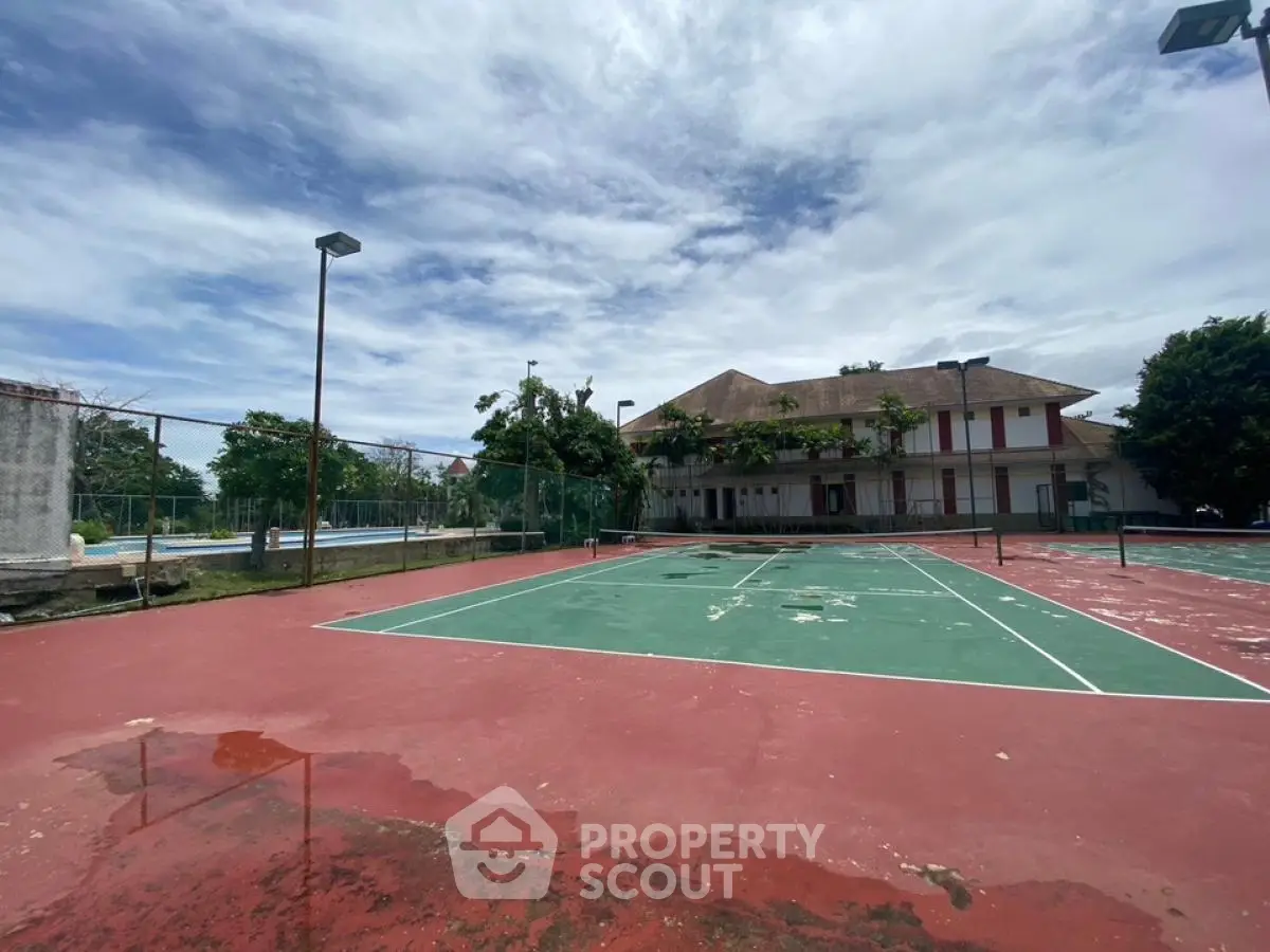 Spacious outdoor tennis court with adjacent building under clear blue sky