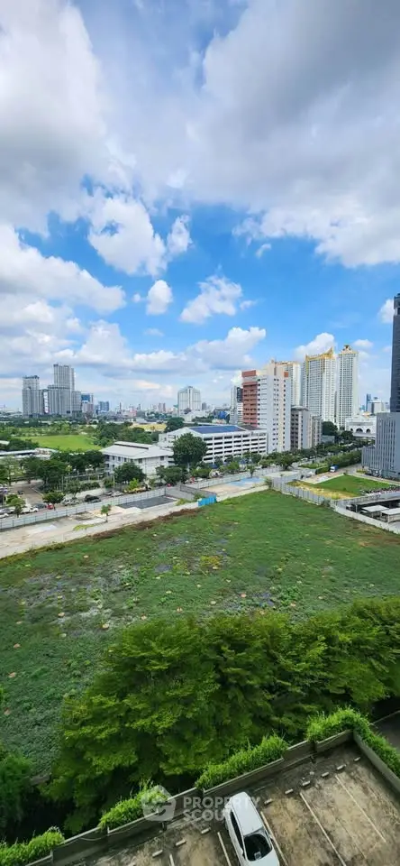 Stunning cityscape view from high-rise building with lush greenery and urban skyline.