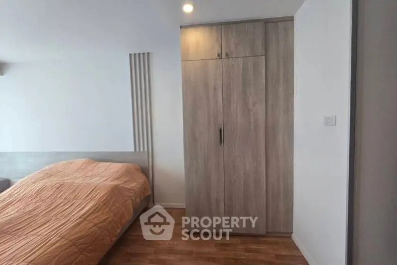 Modern bedroom with wooden flooring and sleek wardrobe design.