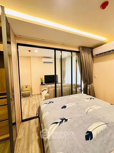 Modern bedroom with sliding glass doors leading to a cozy living area, featuring stylish decor and air conditioning.