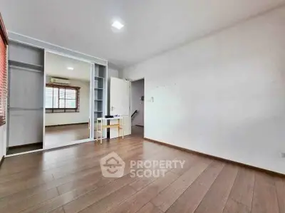 Spacious empty room with wooden flooring and mirrored closet doors, ideal for customization.