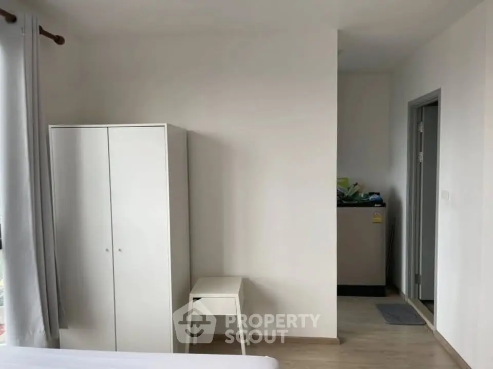 Minimalist bedroom with white wardrobe and washing machine in modern apartment.