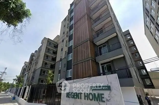 Modern apartment building exterior with balconies and lush surroundings