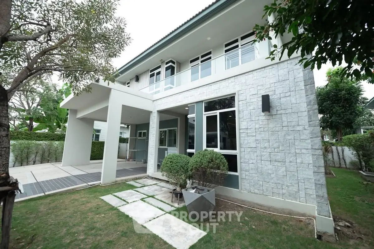 Modern two-story house with stone facade and lush garden