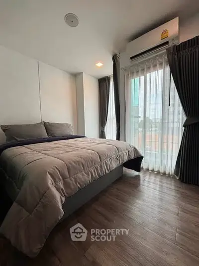 Modern bedroom with large window and stylish decor in urban apartment.