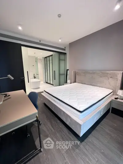 Modern bedroom with stylish decor and ensuite bathroom featuring a luxurious bathtub.