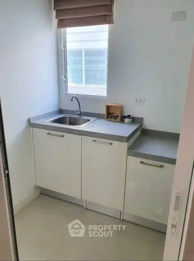 Compact kitchen with modern cabinetry and natural light