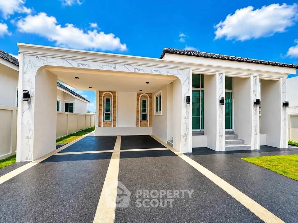 Modern single-story house with elegant facade and spacious driveway under a clear blue sky.