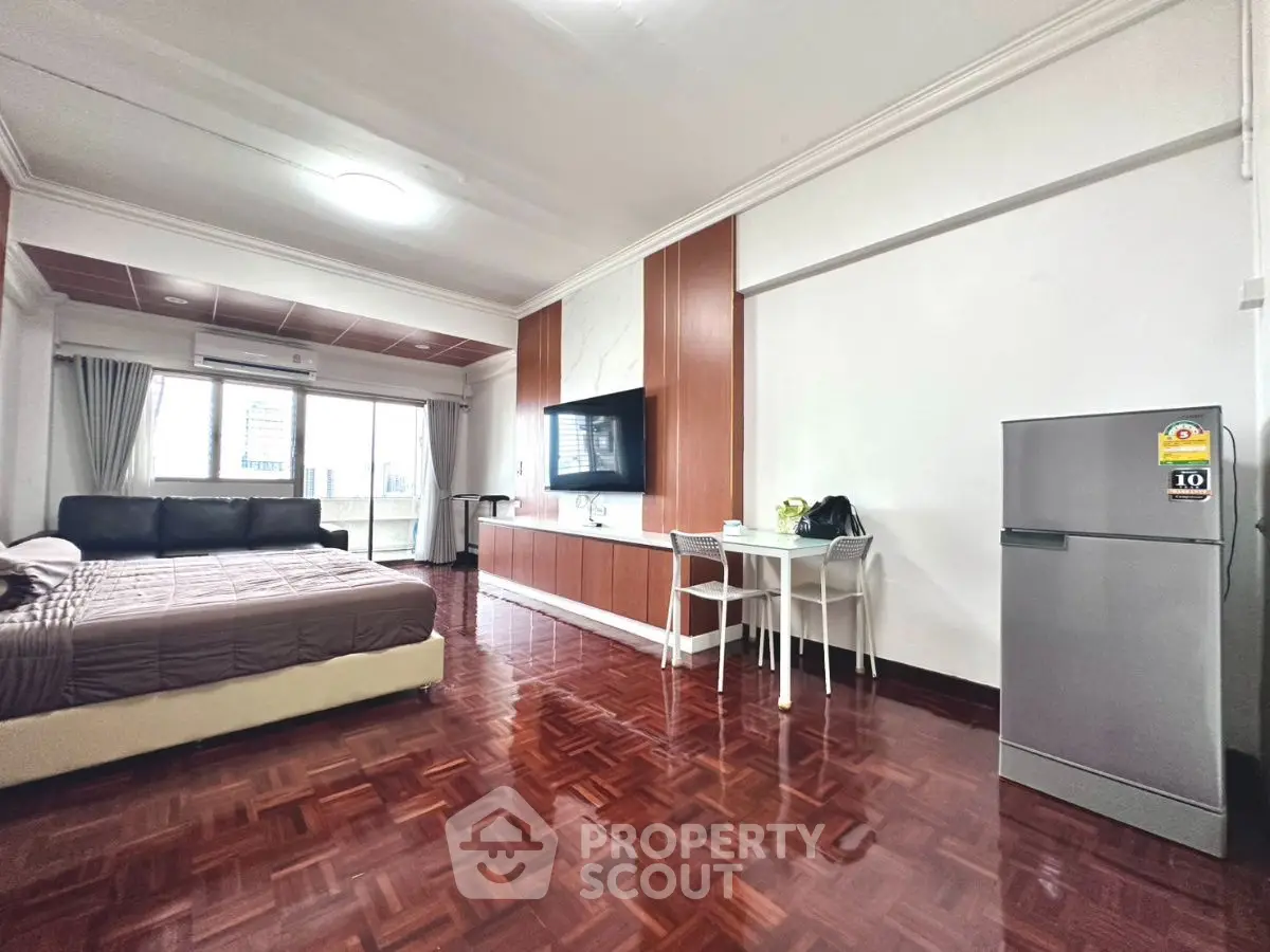 Spacious studio apartment with modern furnishings and hardwood floors.