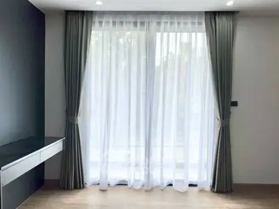 Spacious room with large window and elegant curtains, perfect for natural light and modern living.